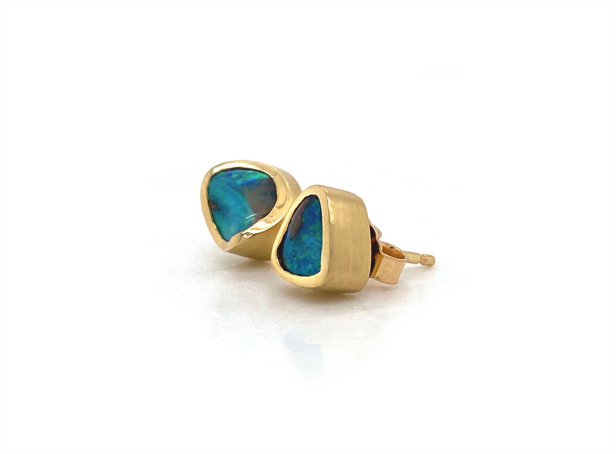 This remarkable pair of hand carved stud earrings showcases two natural Australian boulder opals with  vibrant flashes of oceanic blue and green. These exquisite gems are delicately wrapped in 18kt yellow gold with a luxurious satin finish. These opals are true works of art and will likely become a treasured family heirloom to be handed down form generation to generation.