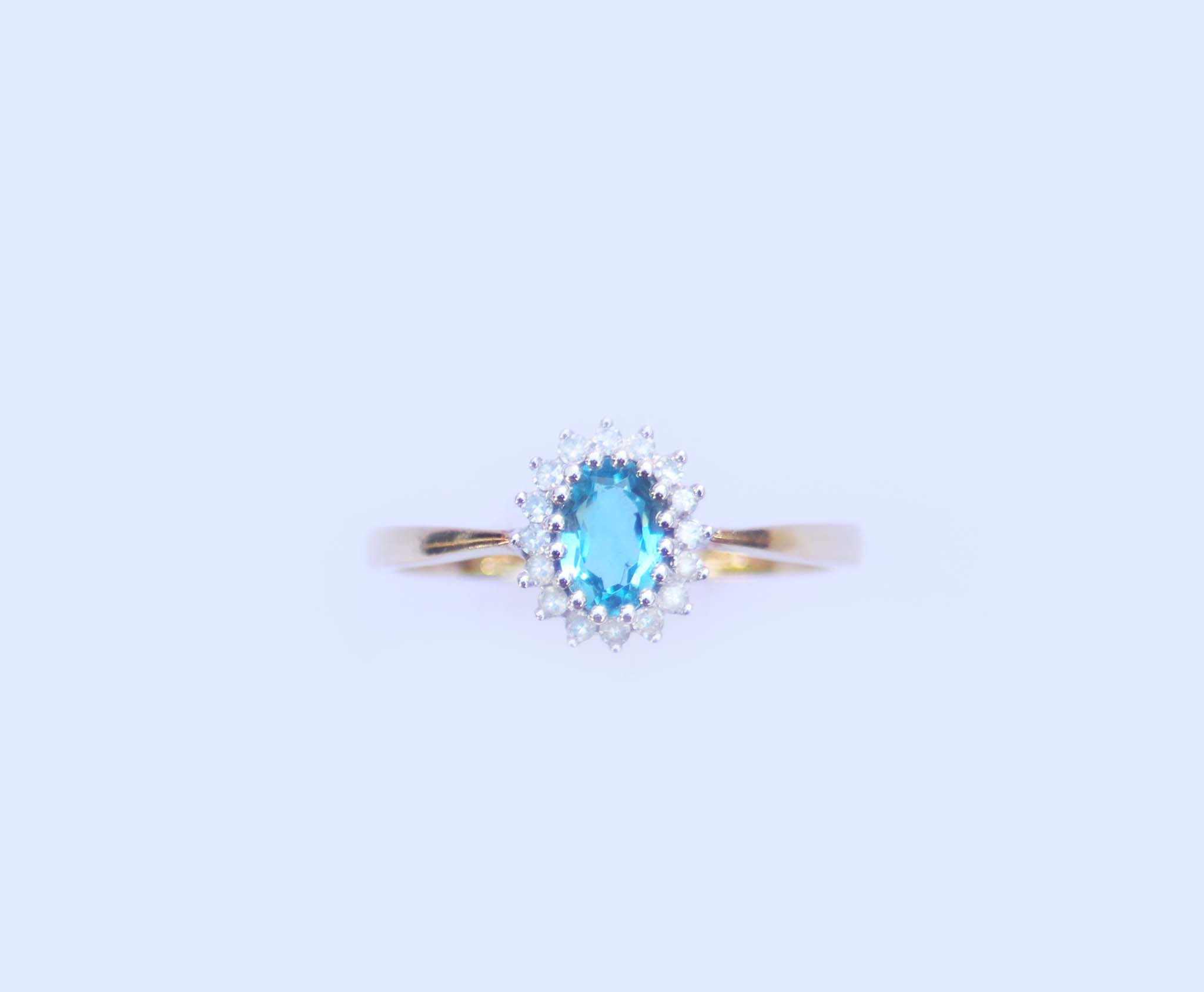 A studio image displaying the front profile of the 9ct yellow gold and 9ct white gold blue topaz and diamond cluster ring.