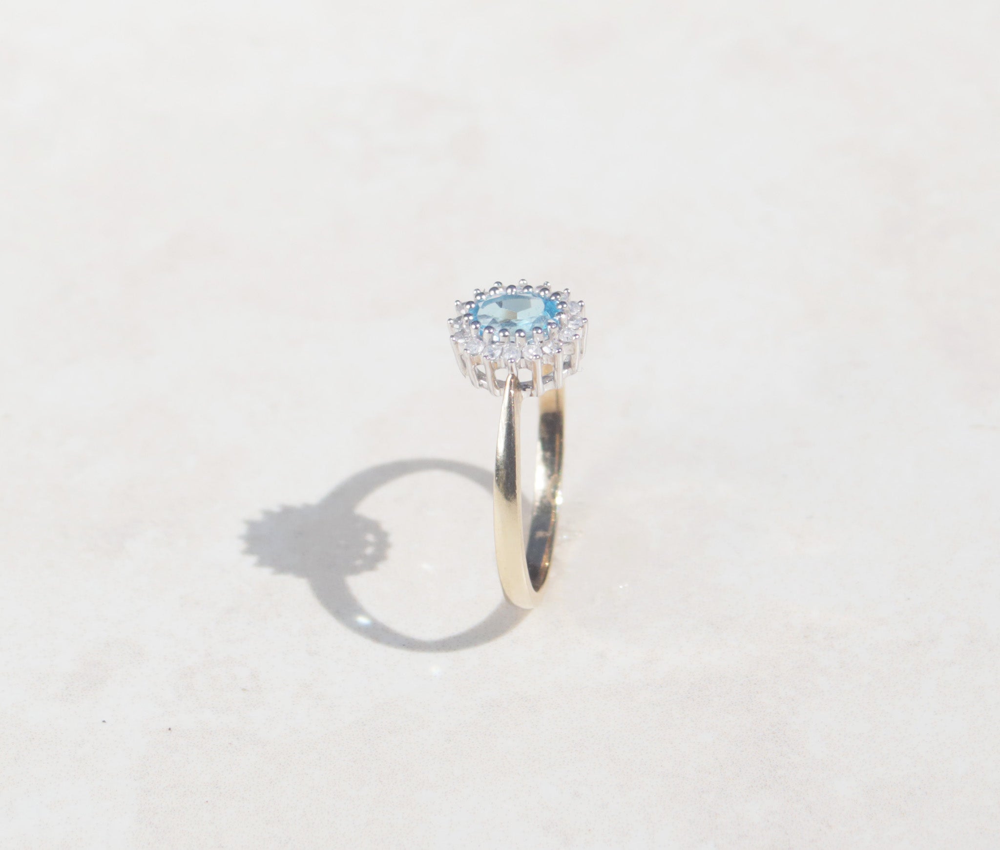 The side profile shows a the 9ct white gold open gallery and tapered shoulders of this ladies 9ct yellow gold and white gold topaz and diamond cluster ring.