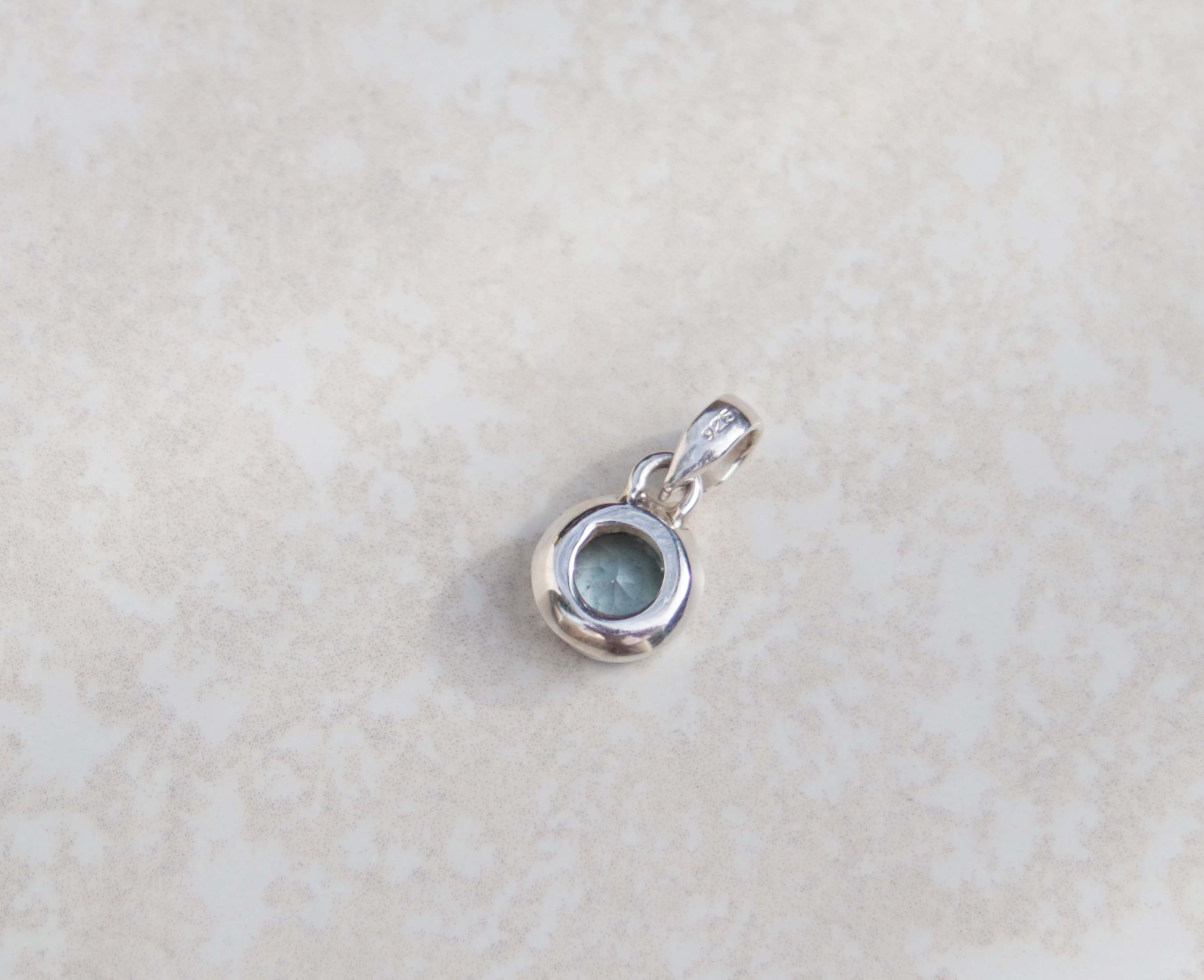 This round pendant features an aquamarine and sterling silver. Dressed with a dainty silver chain, this gem stands out for its vivid sky blue colour and brilliance.