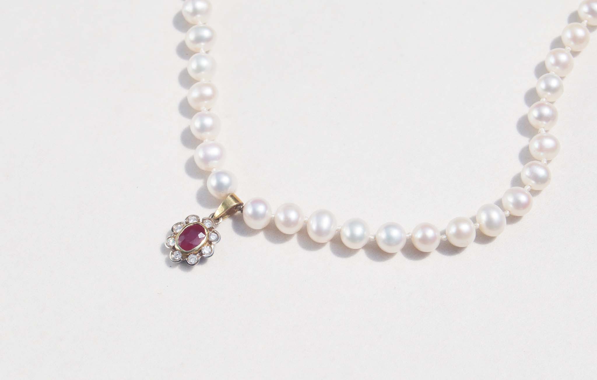 A luxury single strand freshwater pearl necklace decorated with 14ct yellow gold ruby flower pendant. This necklace is made from 62 freshwater pearls, each rich in colour with a lustrous surface.