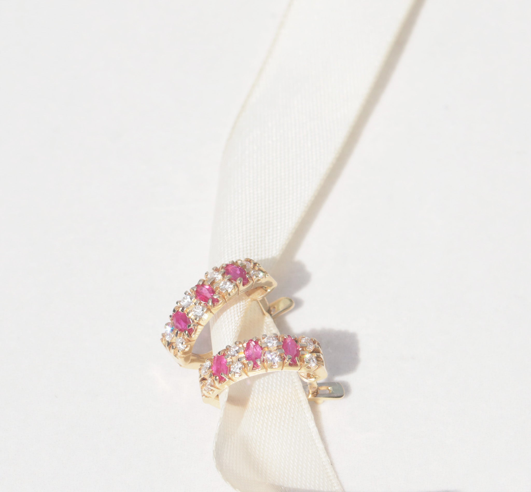 A elegant pair of 18ct yellow gold ruby and diamond earrings. Inspired by traditional designs, each earring features three marquise cut rubies among a family of round brilliant cut diamonds. Comforted by claws, the rubies have a vivid pinkish red colour and gorgeous inner glow. The round brilliant cut diamonds measure 0.05cts, with a total diamond weight of 0.40cts.