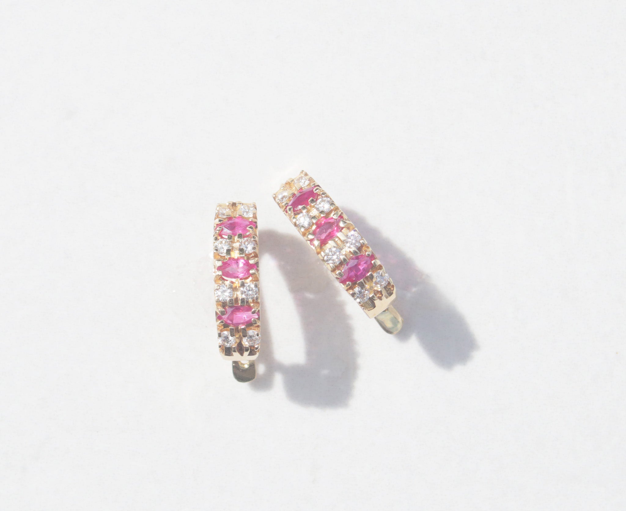 An elegant pair of 18ct yellow gold ruby and diamond earrings.   Inspired by traditional designs, each earring features three marquise cut rubies among a family of round brilliant cut diamonds. Comforted by claws, the rubies have a vivid  pinkish red colour and gorgeous inner glow. The round brilliant cut diamonds measure 0.05cts, with a total diamond weight of 0.40cts.