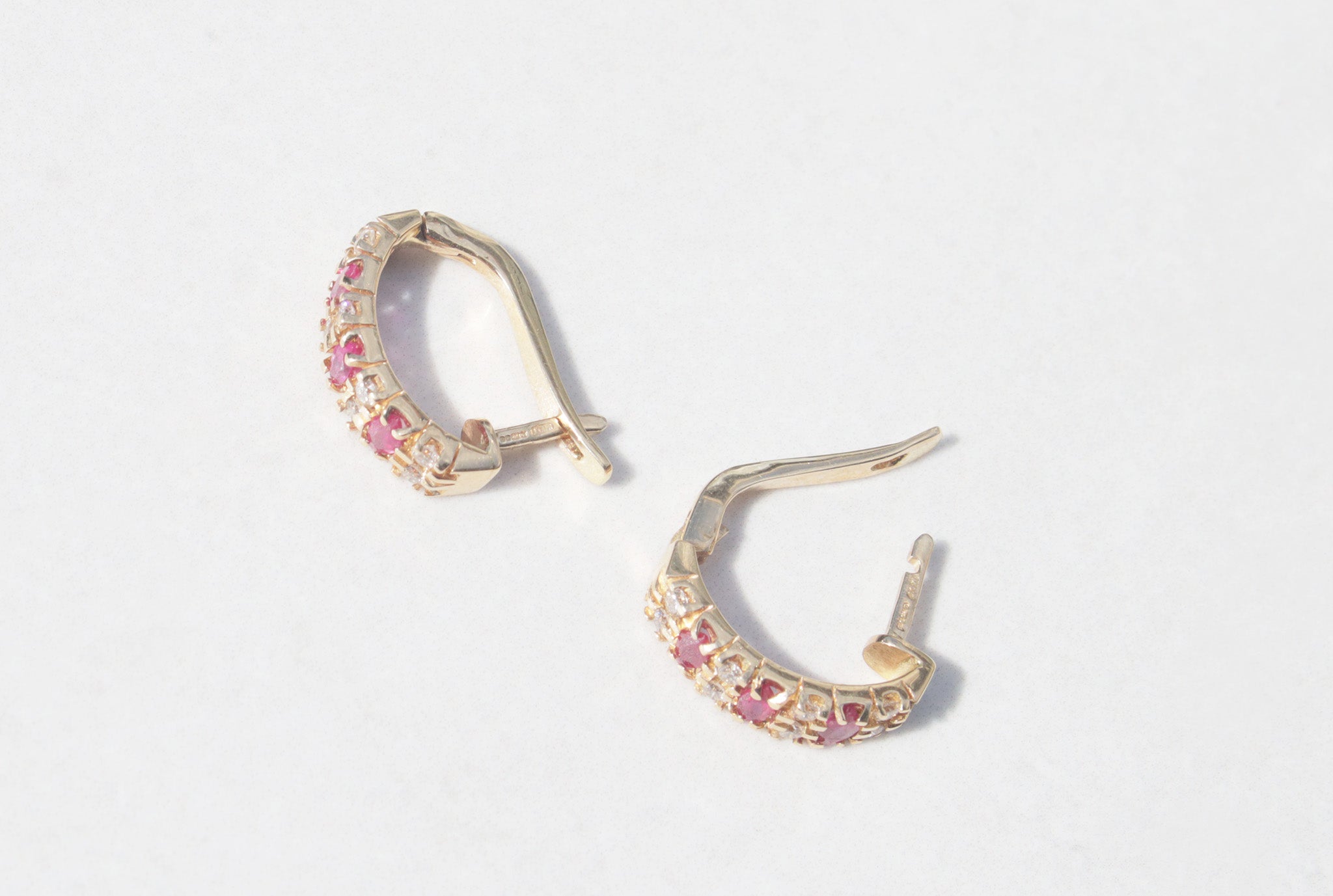 A elegant pair of 18ct yellow gold ruby and diamond earrings.   Inspired by traditional designs, each earring features three marquise cut rubies among a family of round brilliant cut diamonds. Comforted by claws, the rubies have a vivid  pinkish red colour and gorgeous inner glow. The round brilliant cut diamonds measure 0.05cts, with a total diamond weight of 0.40cts.