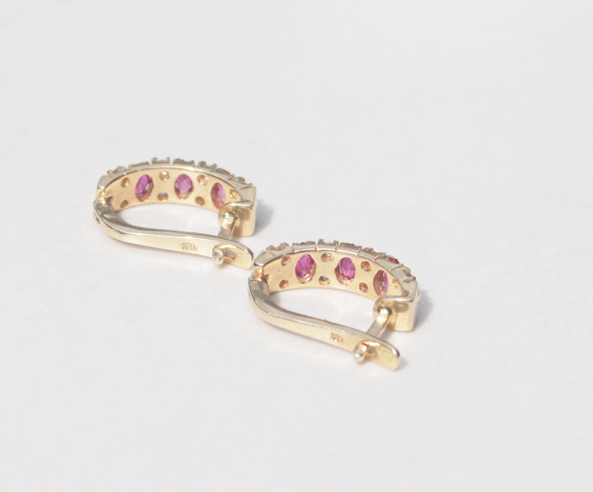 A elegant pair of 18ct yellow gold ruby and diamond earrings. Inspired by traditional designs, each earring features three marquise cut rubies among a family of round brilliant cut diamonds. Comforted by claws, the rubies have a vivid pinkish red colour and gorgeous inner glow. The round brilliant cut diamonds measure 0.05cts, with a total diamond weight of 0.40cts.