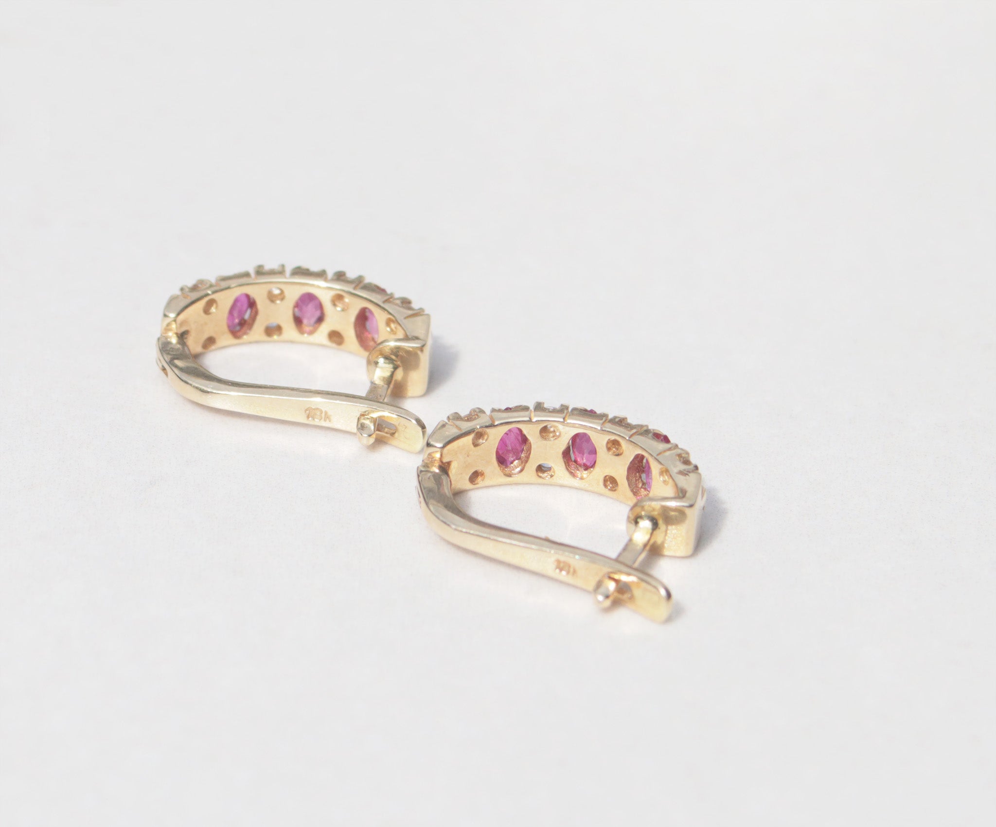 A elegant pair of 18ct yellow gold ruby and diamond earrings.   Inspired by traditional designs, each earring features three marquise cut rubies among a family of round brilliant cut diamonds. Comforted by claws, the rubies have a vivid  pinkish red colour and gorgeous inner glow. The round brilliant cut diamonds measure 0.05cts, with a total diamond weight of 0.40cts. 
