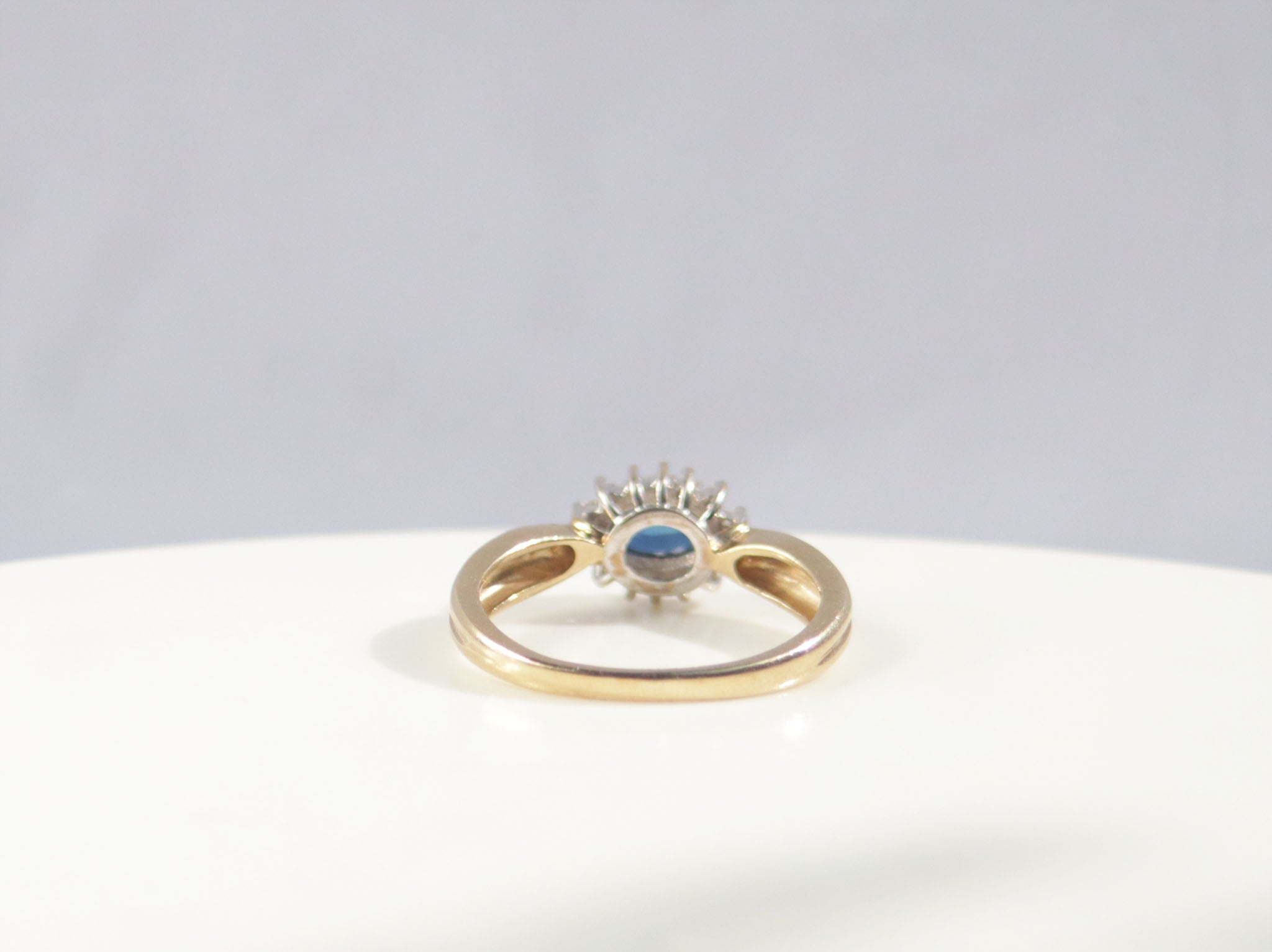 A classic Edwardian inspired sapphire and diamond ring. Crafted from 9ct yellow gold, this classic design features a vivid blue sapphire surrounded by fourteen round brilliant cut diamonds. With a carat weight of 0.75ct, the rich blue sapphire takes centre stage among a cluster of round brilliant diamonds.