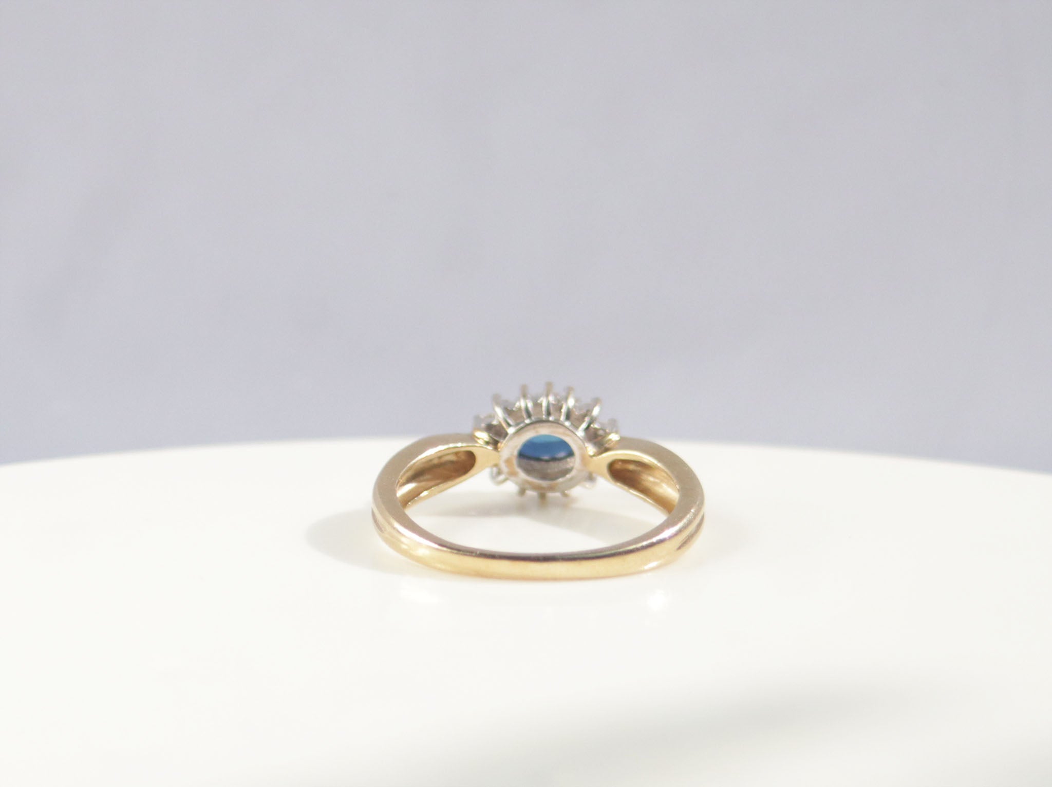 A classic Edwardian inspired sapphire and diamond ring. Crafted from 9ct yellow gold, this classic design features a vivid blue sapphire surrounded by fourteen round brilliant cut diamonds. With a carat weight of 0.75ct, the rich blue sapphire takes centre stage among a cluster of round brilliant diamonds. 