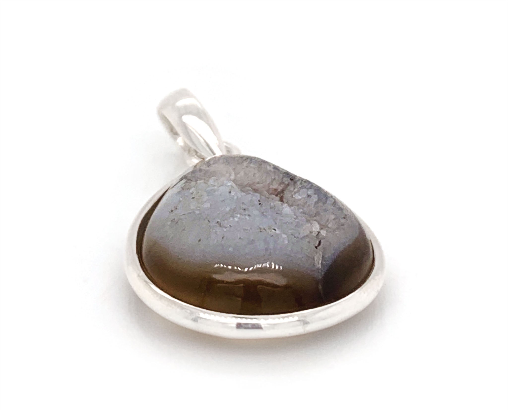 This sterling silver pendant features a Onyx, a variety of chalcedony and a member of the quartz family with a hexagonal crystal system. This gem stands out among others, due to the lustrous colony of crystals formed on its surface known as druzy. This special brown onyx has an visible band across on the top with a unique surface of crystals.