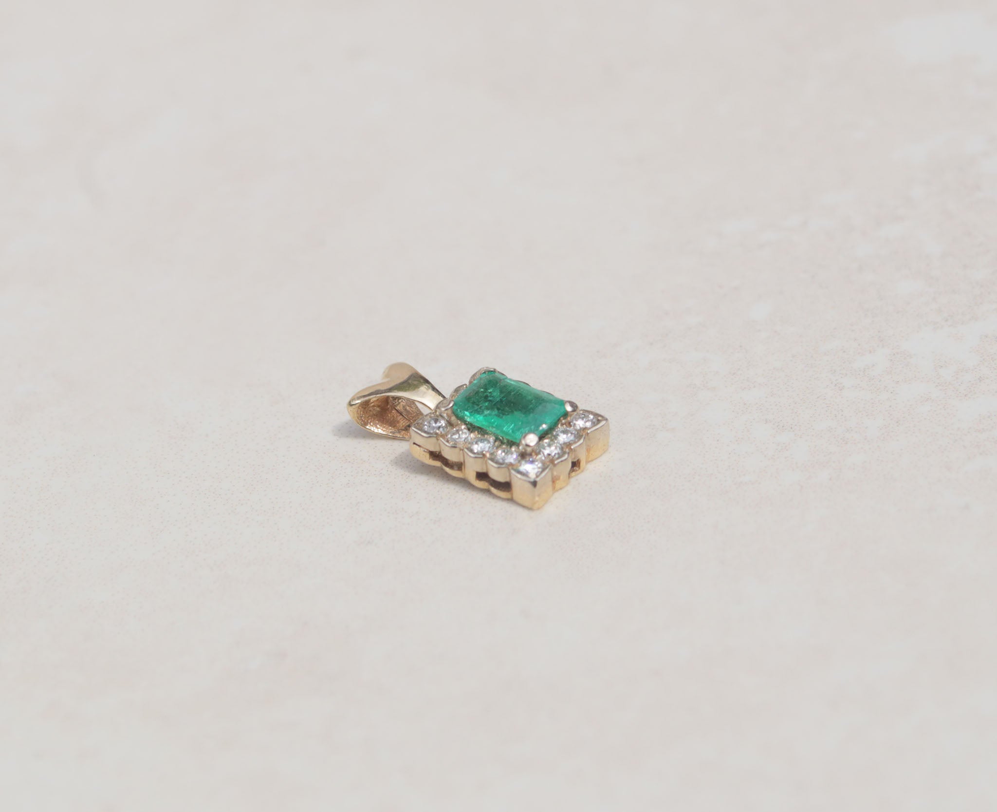 This gorgeous pendant features an emerald gemstone with a diamond halo. Held by slim prongs, the green emerald measures 0.50cts and takes centre stage among rows of round brilliant cut diamonds.  Emerald is the birthstone for May  Emerald celebrates the twentieth and thirty-fifth wedding anniversaries