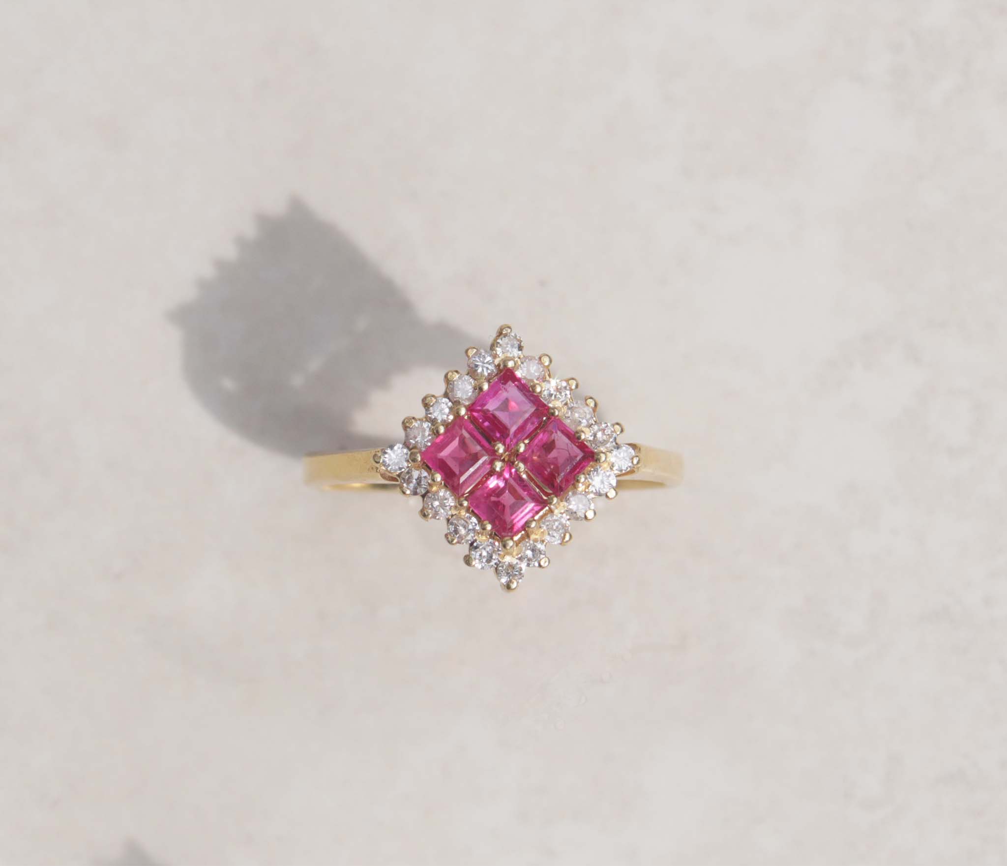 A ladies 18ct yellow gold ruby and diamond vintage ring. This gorgeous piece features four masterfully cut ruby gems. Each gem has a strong red-pink colour with a halo of round brilliant cut diamonds, with a total carat weight of 0.40cts.