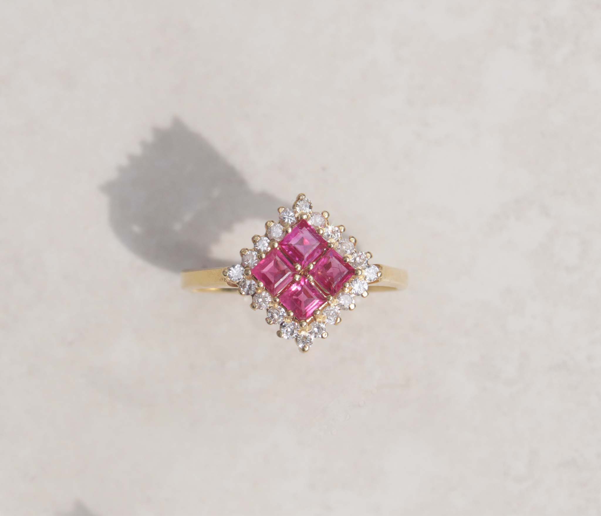 A ladies 18ct yellow gold ruby and diamond vintage ring. This gorgeous piece features four masterfully cut ruby gems. Each gem has a strong red-pink colour with a halo of round brilliant cut diamonds, with a total carat weight of 0.40cts. 