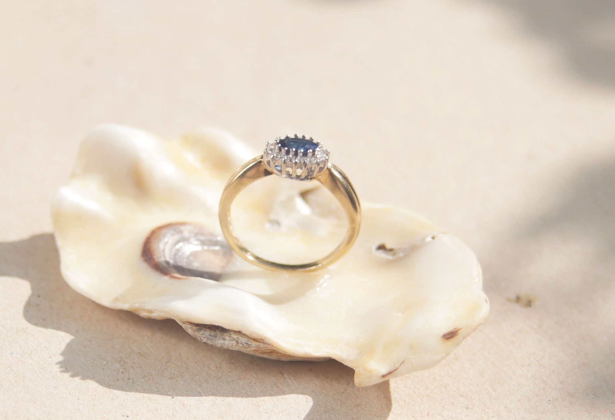 This classic design features a royal blue sapphire surrounded by a cluster of diamonds set in 9kt yellow gold band. The outer claw setting creates an elegant Edwardian aesthetic and makes this ring a real sparkling showstopper.