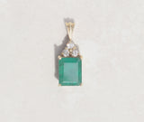 Simple but striking, this yellow gold pendant showcases a three carat Colombian emerald with three round brilliant cut diamonds.   Emerald is the birthstone for May  Emerald celebrates the twentieth and thirty-fifth wedding anniversaries
