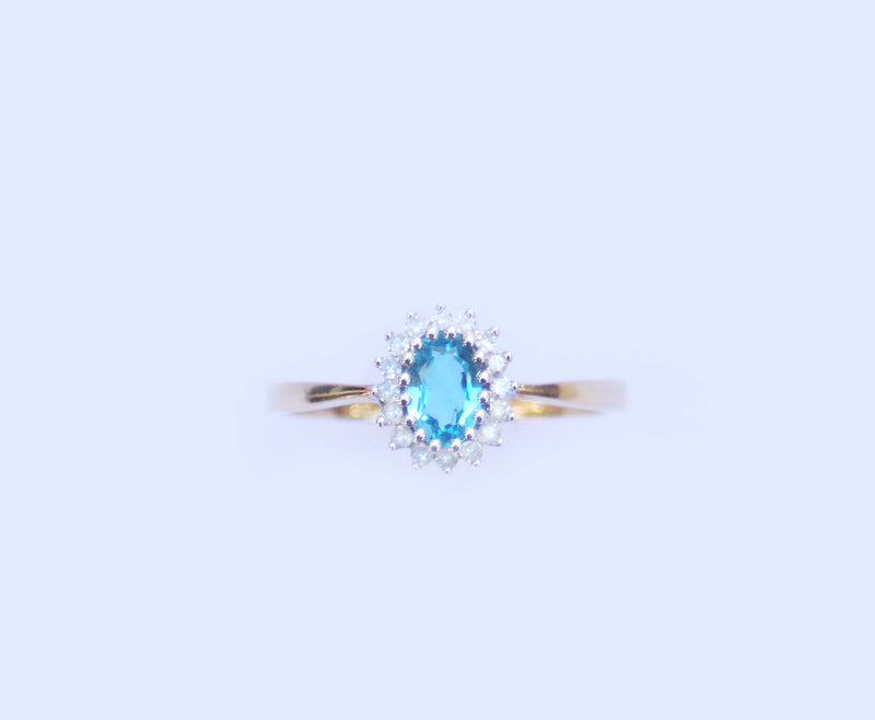 A studio image displaying the front profile of the  9ct yellow gold and 9ct white gold blue topaz and diamond cluster ring. 