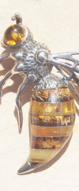 A captivating sterling silver queen bee brooch.   Detailed with texture, this brooch features a beautiful variety of natural amber. Each amber slice contains an array of natural inclusions to reflect the interesting texture and colours of the queen bee's body. The sterling silver body has been oxidised and finished with a bright amber eye.    Within the bee hive, the queen bee is said to be symbolic of femininity, motherhood empowerment and growth.   This brooch will elevate both formal and everyday wear. 