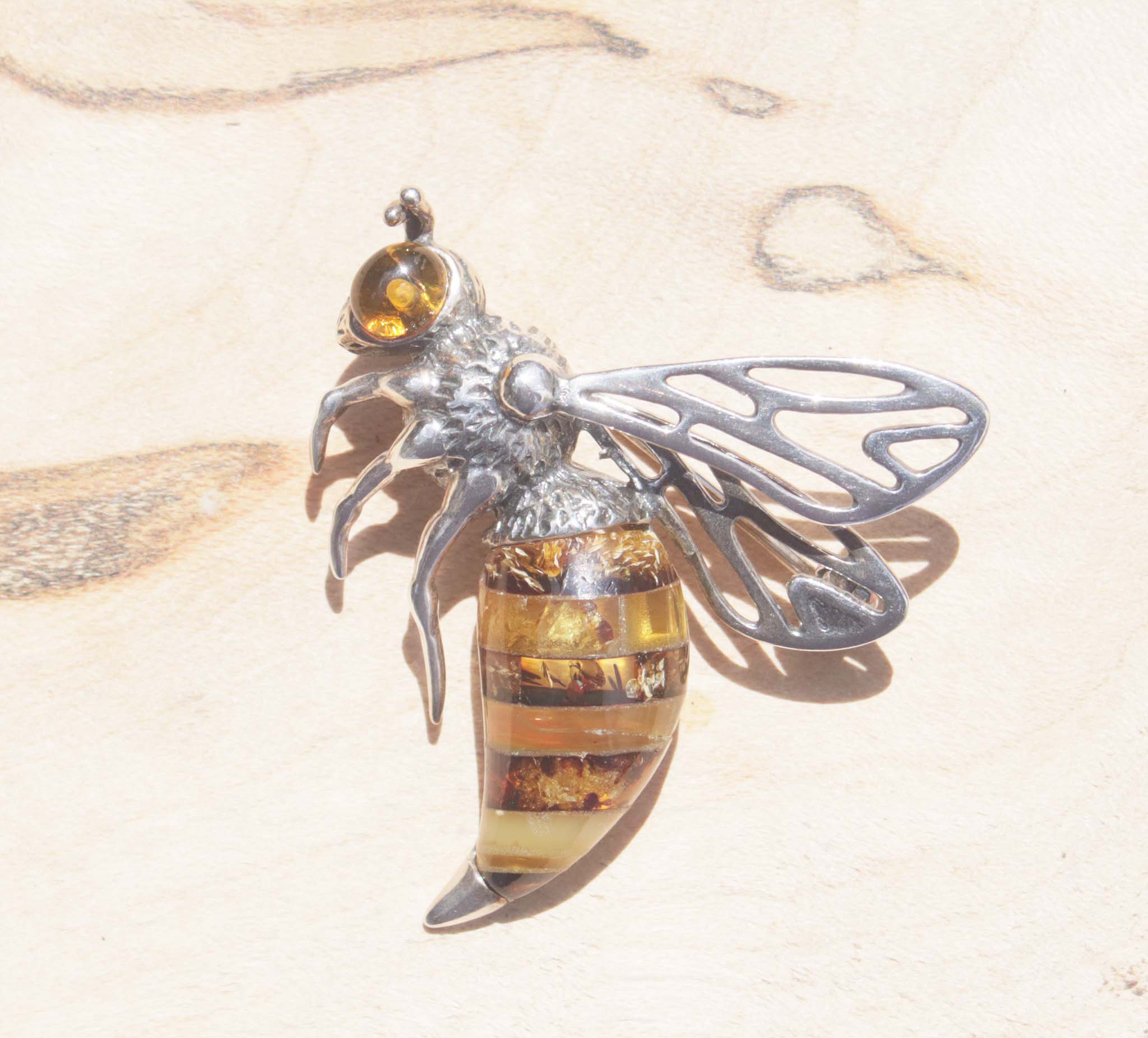 A captivating sterling silver queen bee brooch.   Detailed with texture, this brooch features a beautiful variety of natural amber. Each amber slice contains an array of natural inclusions to reflect the interesting texture and colours of the queen bee's body. The sterling silver body has been oxidised and finished with a bright amber eye.    Within the bee hive, the queen bee is said to be symbolic of femininity, motherhood empowerment and growth.   This brooch will elevate both formal and everyday wear. 