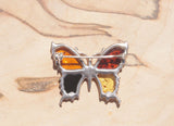 An eye-catching sterling silver amber butterfly brooch.   This brooch contains a variety of natural amber, a natural material made from the resin of trees. Set in sterling silver, the amber wings include cognac, honey, orange and green amber.  This image shows the back of the brooch.