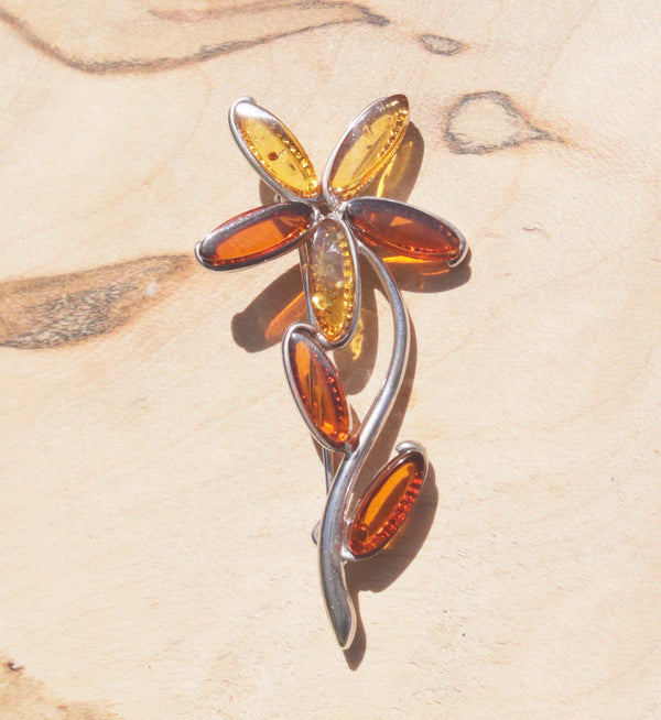 A beautiful sterling silver amber flower brooch.   Each petal displays a variety of honey and cognac natural amber, finished with two cognac leaves. 