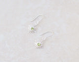 This pair of silver hook earrings feature a dainty star centered with peridot gems. The colour of the centre gem is bright green 