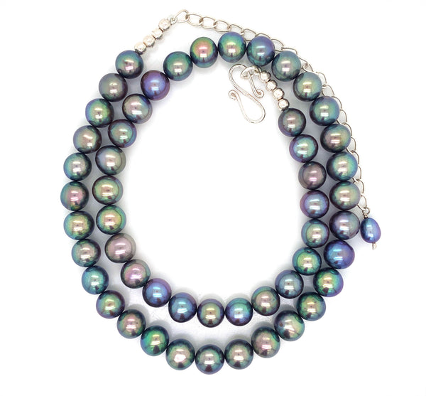 This elegant 20" inch necklace features a string of Tahitian pearls, a natural lustrous material known for its iridescent play of colours ranging from light metallic grey, blue to dark green. This necklace comes with a pair of matching Tahitian pearl ball hook earrings. This necklace includes 51 pearls in total with a circumference of 7 mm with an hallmarked sterling silver S lock