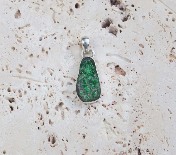 A sterling silver uvarovite garnet pendant. This gem has an attractive moss green colour and natural textured surface.  Uvarovite Garnet is one of the rarest members of the garnet family.