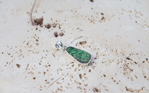 A sterling silver uvarovite garnet pendant. This gem has an attractive moss green colour and natural textured surface.  Uvarovite Garnet is one of the rarest members of the garnet family.