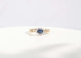 A classic Edwardian inspired sapphire and diamond ring. Crafted from 9ct yellow gold, this classic design features a vivid blue sapphire surrounded by fourteen round brilliant cut diamonds. With a carat weight of 0.75ct, the rich blue sapphire takes centre stage among a cluster of round brilliant diamonds.