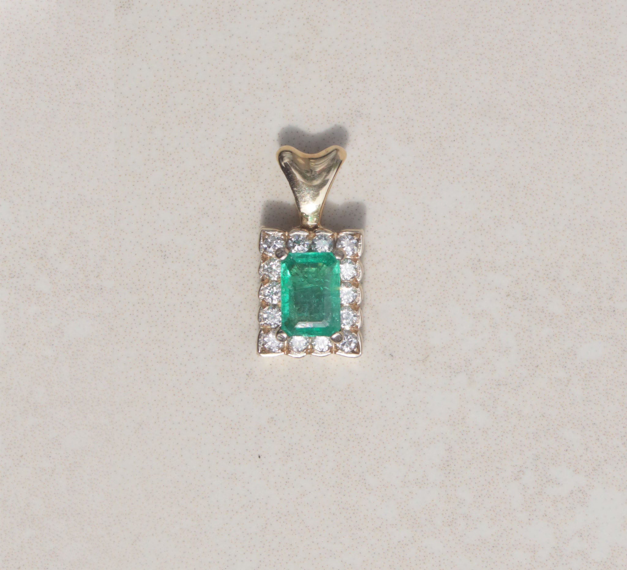 This gorgeous pendant features an emerald gemstone with a diamond halo. Held by slim prongs, the green emerald measures 0.50cts and takes centre stage among rows of round brilliant cut diamonds.  Emerald is the birthstone for May  Emerald celebrates the twentieth and thirty-fifth wedding anniversaries
